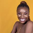 Enjoy a lively studio portrait of a smiling woman with braids against a yellow backdrop.