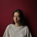 Studio portrait of a woman in a white shirt against a red background.